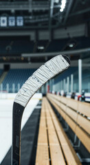 Ice hockey stick resting on bench in an empty arena  