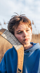 Young boy with hockey stick looking thoughtfully in tall grass  