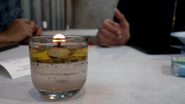 Candles in small glasses on the dining table. Aromatherapy oil candles to repel insects. Dining setup. Table top. Concept.