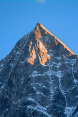Illuminated Alpine Peak at Sunrise Against Clear Blue Sky