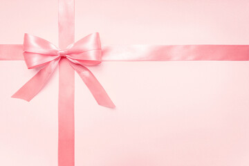 Pink satin ribbon and bow on pastel background with copy space, horizontal