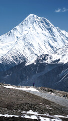 Lone Hiker Under Majestic Snowcapped Mountain Peak with Clear Blue Sky