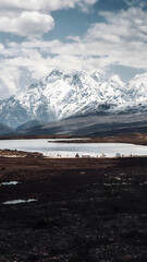 Snowcapped Alpine Peaks Reflected in Mountain Lake with Dramatic Sky