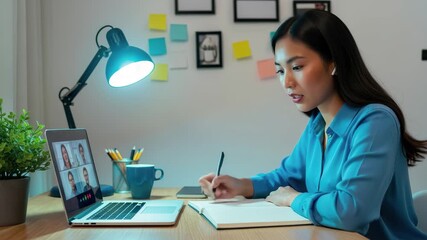 Focused professional woman collaborating remotely, taking notes during a virtual team meeting at her desk. 4k high quality footage - Powered by Adobe