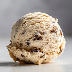 Creamy Vanilla Ice Cream Scoop with Raisins and Dark Brown Swirls on White Surface with Soft Lighting