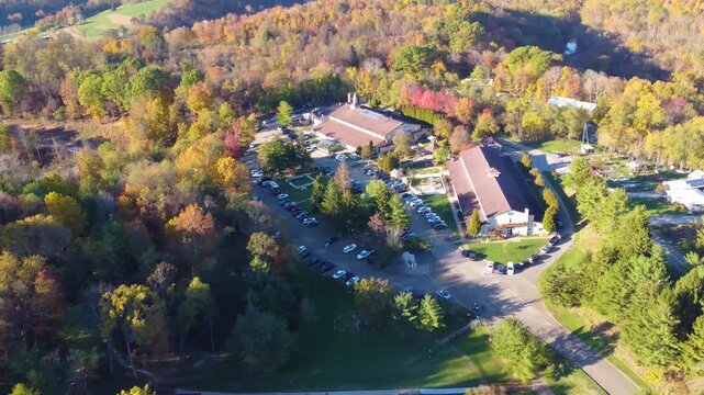 Aerial view of the ISKCON New Vrindaban Temple surrounded by dense forest and vibrant fall foliage, showcasing the temple nestled in a jungle of golden autumn colors