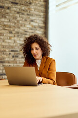 Professional Woman Working On Laptop At Modern Office With Brick Wall Backdrop For Remote Work