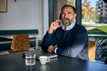 Professional Man on Phone at Modern Café With Laptop, Coffee, and Calm Focus