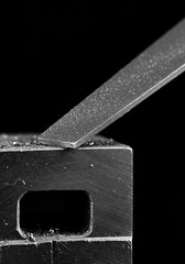 Textured surface of a workpiece being meticulously shaped by a metal file, highlighting the abrasive process and industrial craftsmanship ,smoothing ,steel ,deburring