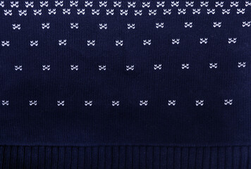 Horizontal or vertical Christmas background with knitted fabric texture. Wool sweater texture of dark blue color with white border. Natural knitted wool indigo color material with white ornament