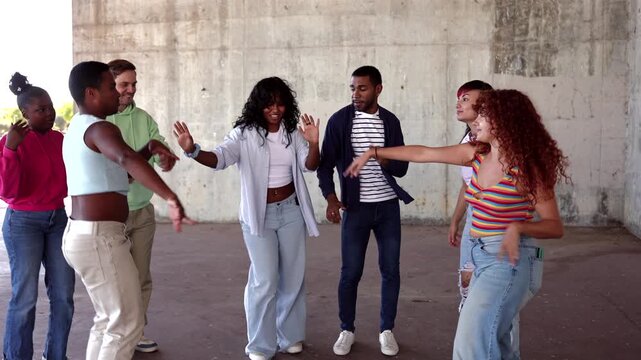 Multicultural young people laughing and having fun while dancing to music outdoors against a concrete wall. Energetic friends enjoying a party together with synchronized and freestyle moves - Powered by Adobe