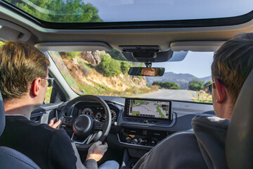 A focused driver sits behind the wheel in a modern car, navigating busy city streets. A large GPS display guides the route, highlighting the tech-enabled, urban driving experience.