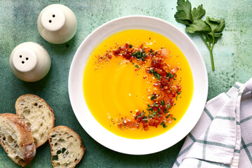 Autumn pumpkin soup with smoked bacon in a blue plate. Top view with copy space.