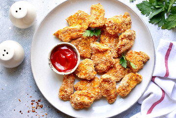 Fresh  homemade crispy chicken nuggets with ketchup on a plate . Top view with copy space.