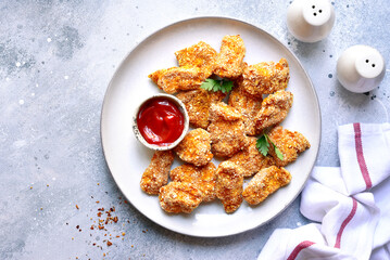 Fresh  homemade crispy chicken nuggets with ketchup on a plate . Top view with copy space.