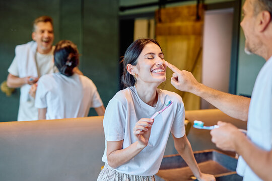 Happy couple engaging in a playful morning routine in the bathroom, enjoying a moment of togetherness and lightheartedness
