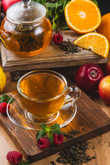 Tea in a glass mug on the table next to mint, raspberries and fruits