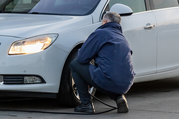 person inflating car tire at gas station
