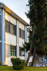 modern building facade with horizontal window blinds and evergreen trees