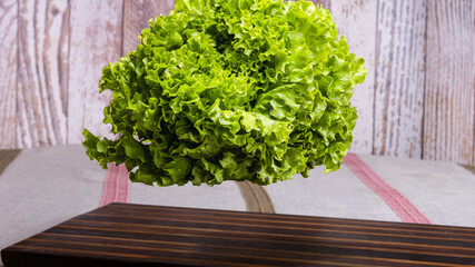 fresh green lettuce floating above wooden board
