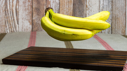 bunch of fresh bananas floating above wooden board