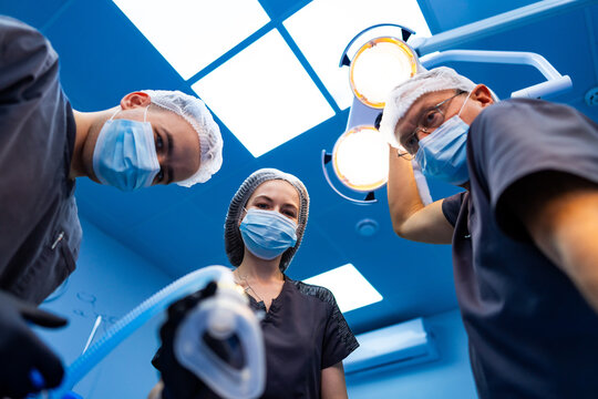 Surgical team with anesthesia mask. Team of surgeons leaning over patient with anesthesia mask ready.