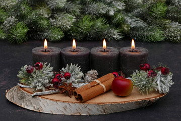 Vierter Advent: Adventskranz mit braunen Kerzen, Zimtstangen, Beeren, Tannenzweigen und Textfreiraum. 