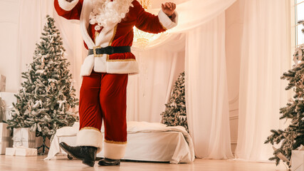 Obraz premium Santa Claus in a festive room with Christmas trees and gifts