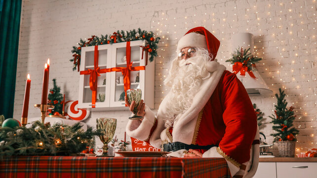 Santa Claus in a festive kitchen setting, raising a glass for a Christmas toast