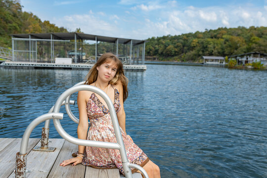 teenager sitting on swim dock surrounded by lake and trees