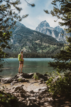 Woman hiker stands on shore of Taggart Lake, Teton National Park