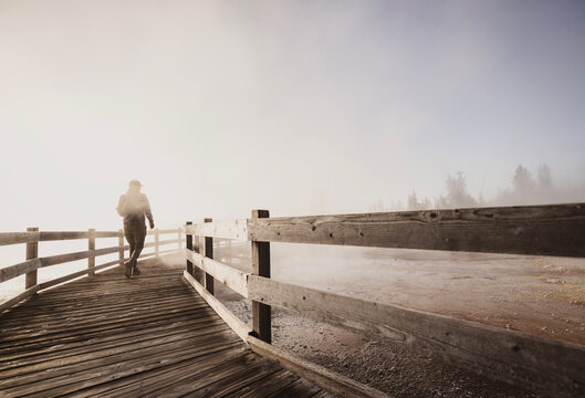 hiker walks through volcanic steam while hiking in Yellowstone
