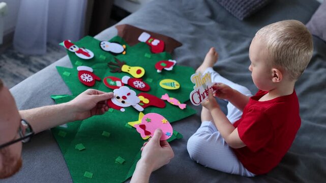 Little boy decorating toy Christmas tree together with his father. Christmas holidays concept. 4K