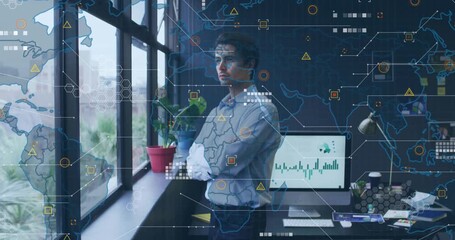 Male analyst standing by window analyzing data starting animating global IT map overlays around him - Powered by Adobe