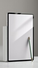 A sleek tablet stands upright next to a thin book, with a stylus pen leaning against its screen, set against a minimalist background.