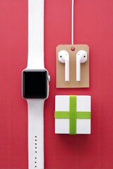 A collection of modern electronic devices, including a smartwatch, wireless earbuds, and a gift box, are neatly arranged on a vibrant red background.