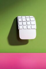 A white numeric keypad with a sleek design is positioned on a vibrant green surface, casting a distinct shadow.