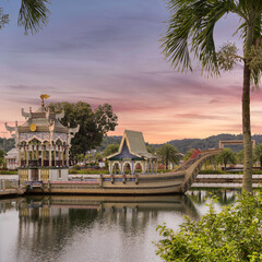 Mahligai Royal Barge on a lake at Sultan Omar Ali Saifuddien Mosque, Bandar Seri Begawan, Brunei. Ornate boat under a vibrant sunset sky, framed by palm fronds.
