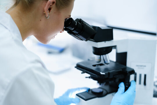 A pharmaceutical Quality Control QC team ensures GxP compliance. Two scientists review an electronic batch record on a tablet while a third performs a required analytical test.