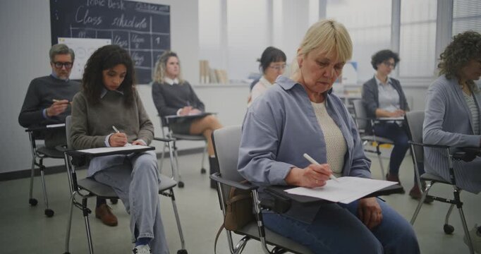 Multicultural Group Of Mature Students Taking Notes During Lesson in Bright Classroom. Students Note Lectures Given by Teacher. Concept Continuing Education, Adult Learning, and Knowledge Development.