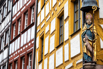 Bishop statue on a historic building with colorful timber-frame houses in Nuremberg’s old town.