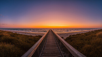 Wooden boardwalk leading to the ocean at sunset with beautiful colors in the sky