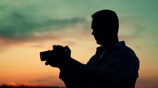 Man photographer taking photo with camera beautiful landscape at dawn against amazing sky. Man traveler with camera, backpack, Silhouette. Photographer taking beautiful photos of nature at sunset.