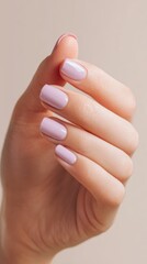 A close-up of a feminine hand displaying perfectly manicured lavender nails against a soft, neutral background, ideal for beauty, manicure or nail care promotions,