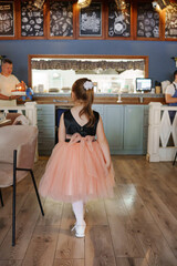 Little girl in a pink dress walking in a cafe