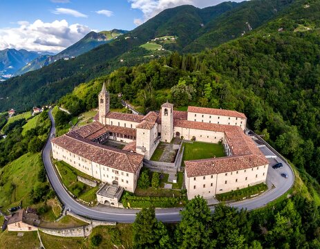 Aerial view of a historic monastery nestled in a lush, green mountain range
