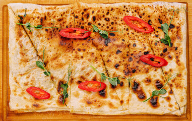 Freshly baked flatbread is presented on a wooden board
