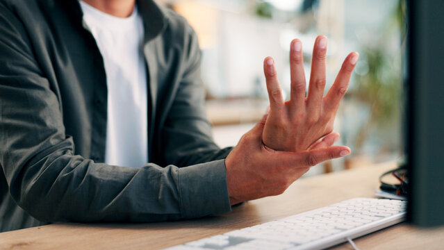 Computer, man and hands in office with wrist pain from fatigue, fibromyalgia and joint inflammation. Exhausted, person and keyboard in workplace with arthritis, carpal tunnel syndrome and discomfort.