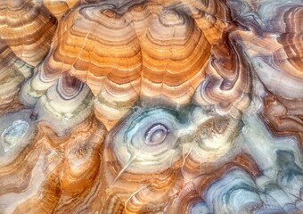 Aerial view of swirling, multicolored rock formations create an otherworldly landscape of layered textures and tones, Hanksville, Utah, United States.