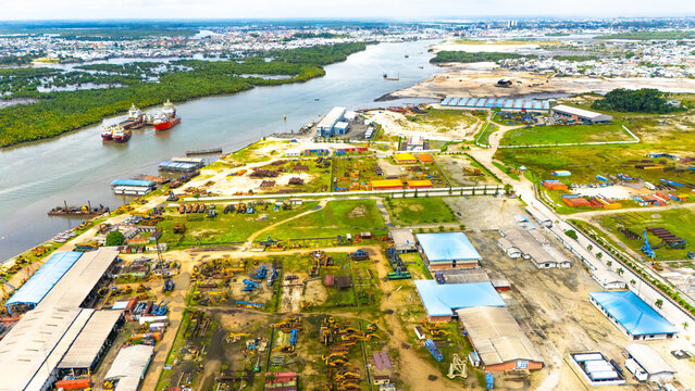 Aerial view of cargo ships resting on the river and industrial operations sprawling across the land contrasting with lush greenery, Abuloma, Port Harcourt, Nigeria.